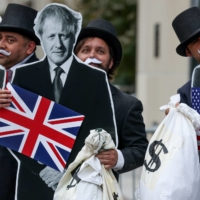 Activists dressed as debt collectors protest outside the IMF-World Bank headquarters in Washington on Oct. 13. | REUTERS