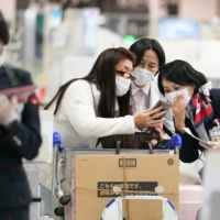 An employee assists travelers at Narita Airport in Chiba Prefecture on Nov. 30. | BLOOMBERG