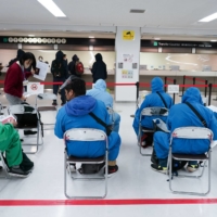 Travelers arriving via a Philippine Airlines flight fill out paperwork at a screening area at Narita Airport in Chiba Prefecture on Nov. 30. | BLOOMBERG