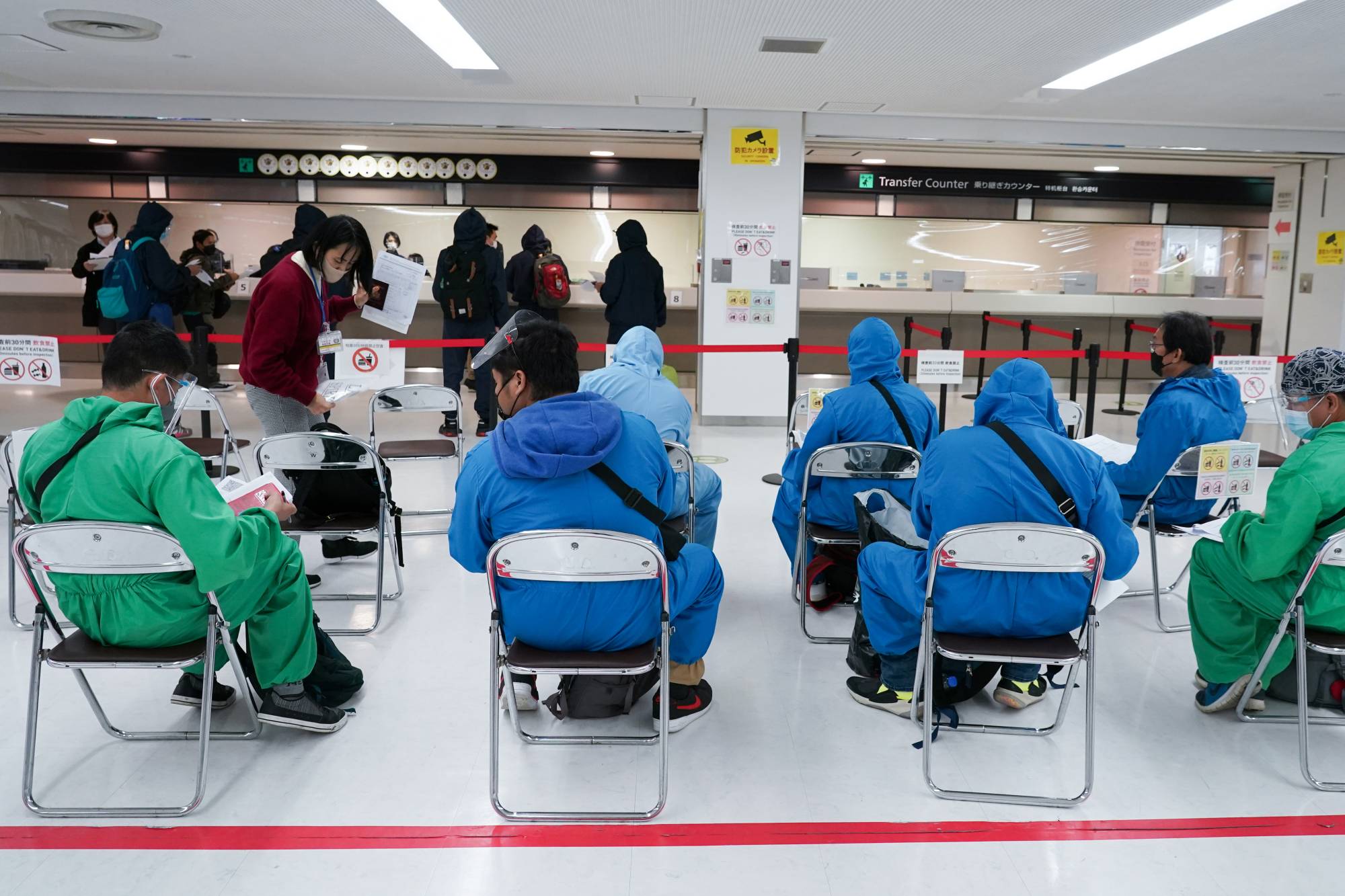 Travelers arriving via a Philippine Airlines flight fill out paperwork at a screening area at Narita Airport in Chiba Prefecture on Nov. 30. | Bloomberg