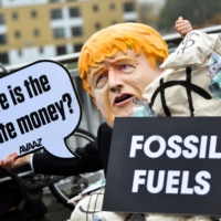 A person wearing a mask depicting Britain\'s Prime Minister Boris Johnson protests during COP26 in Glasgow in Nov. 2021. | REUTERS