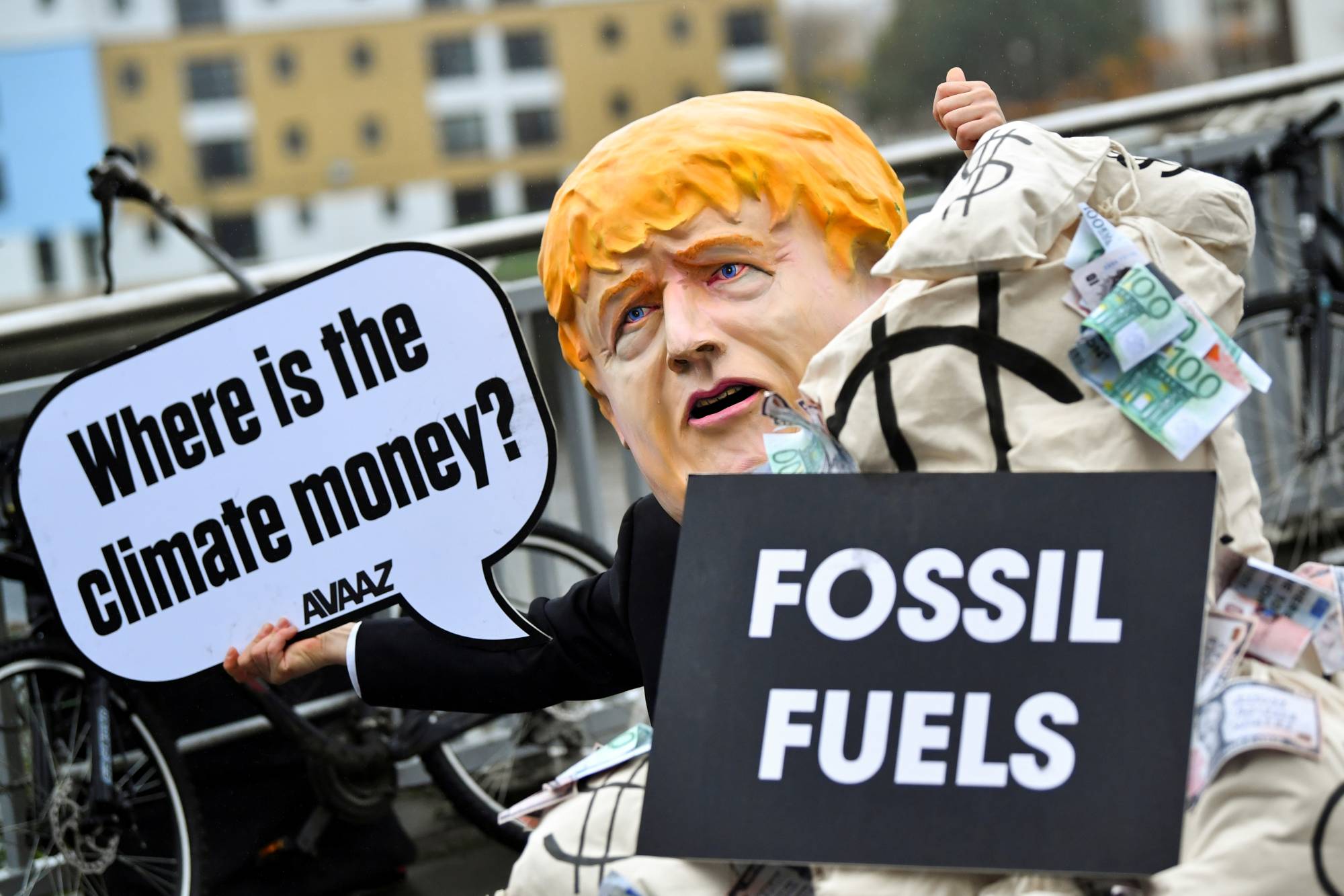 A person wearing a mask depicting Britain's Prime Minister Boris Johnson protests during COP26 in Glasgow in Nov. 2021. | REUTERS