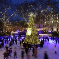 Ice skaters skate around the Christmas tree on the ice rink at the Natural History Museum in central London on Thursday. | AFP-JIJI