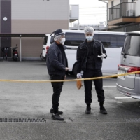 Police officers shield an area near an apartment building in Moriyama, Shiga Prefecture, on Monday, after a female high school student was found collapsed inside the residence the previous day. | KYODO