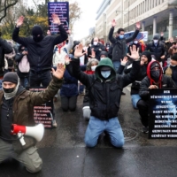 Demonstrators kneel down after police officers ended a protest against government measures to curb the spread of COVID-19 in Frankfurt on Dec. 4. | REUTERS 
