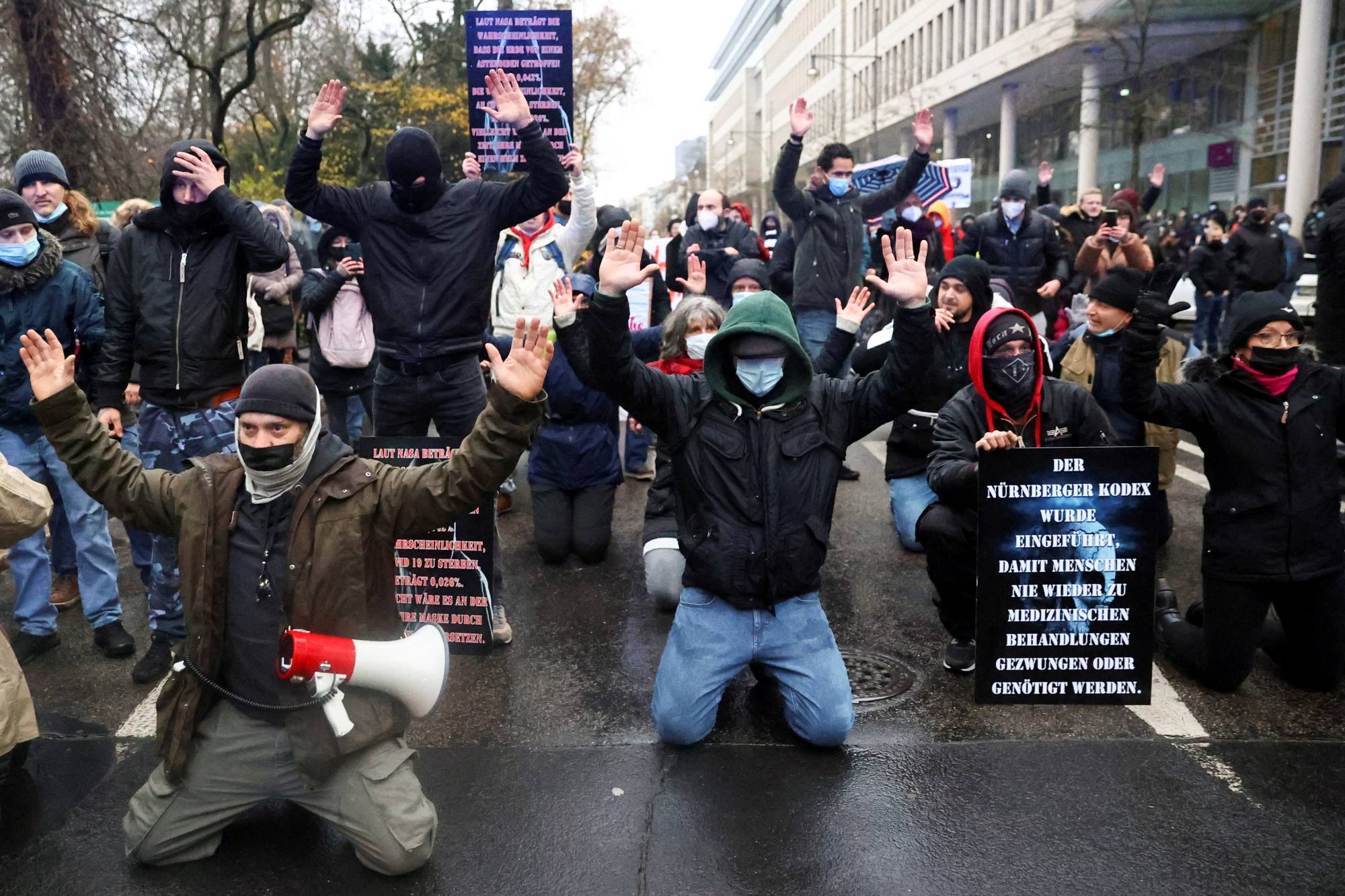 Demonstrators kneel down after police officers ended a protest against government measures to curb the spread of COVID-19 in Frankfurt on Dec. 4. | Reuters 