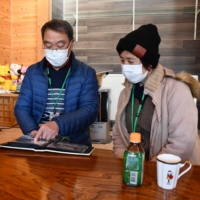 Kazuo Naito and his wife, Mitsuko, look at a family album in Katsurao, Fukushima Prefecture, on Nov. 30. | FUKUSHIMA MINPO