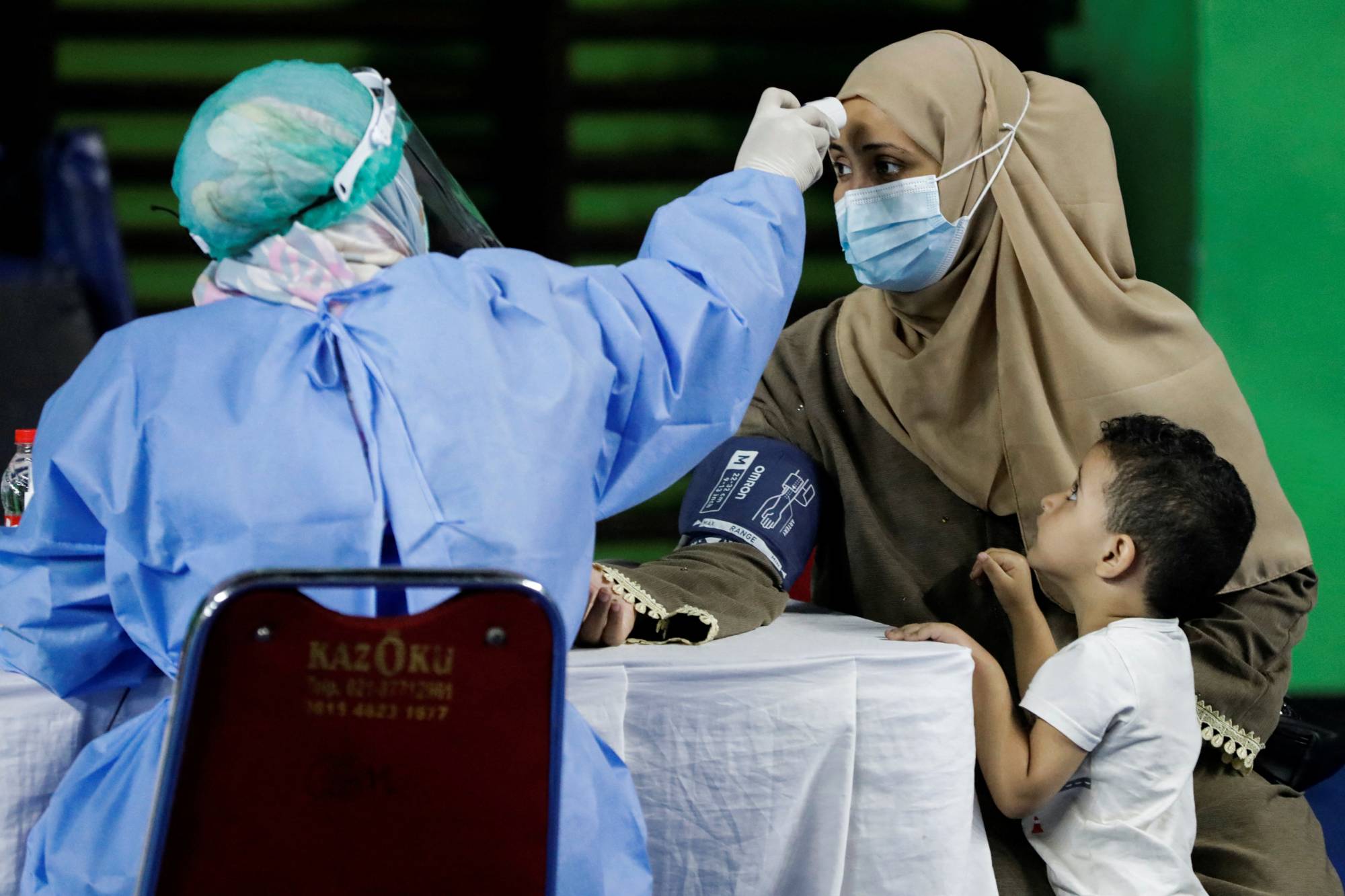 A woman undergoes a health screening before receiving a dose of a COVID-19 vaccine during a mass vaccination program for asylum seekers and refugees at a sports hall in Jakarta in Oct., 2021. | REUTERS