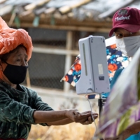 A woman uses the hand sanitizer dispenser at Thamhin refugee camp in Thailand in Oct., 2021.  | REUTERS
