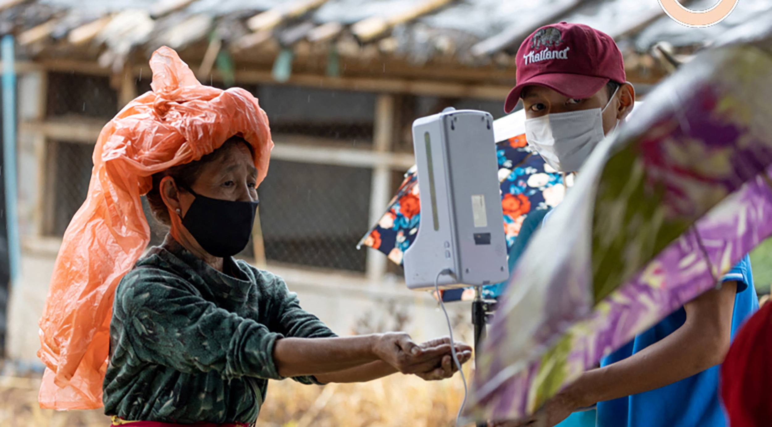 A woman uses the hand sanitizer dispenser at Thamhin refugee camp in Thailand in Oct., 2021. | REUTERS