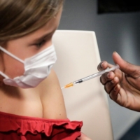 A child receives a dose of the Pfizer/BioNTech COVID-19 vaccine in Paris on Friday. | AFP-JIJI