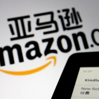 The sign of e-commerce website Amazon China is seen next to a Kindle e-reader. | REUTERS