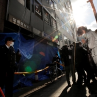 A person prays for the victims Saturday in front of an Osaka building where a fire broke out the day before.  | REUTERS