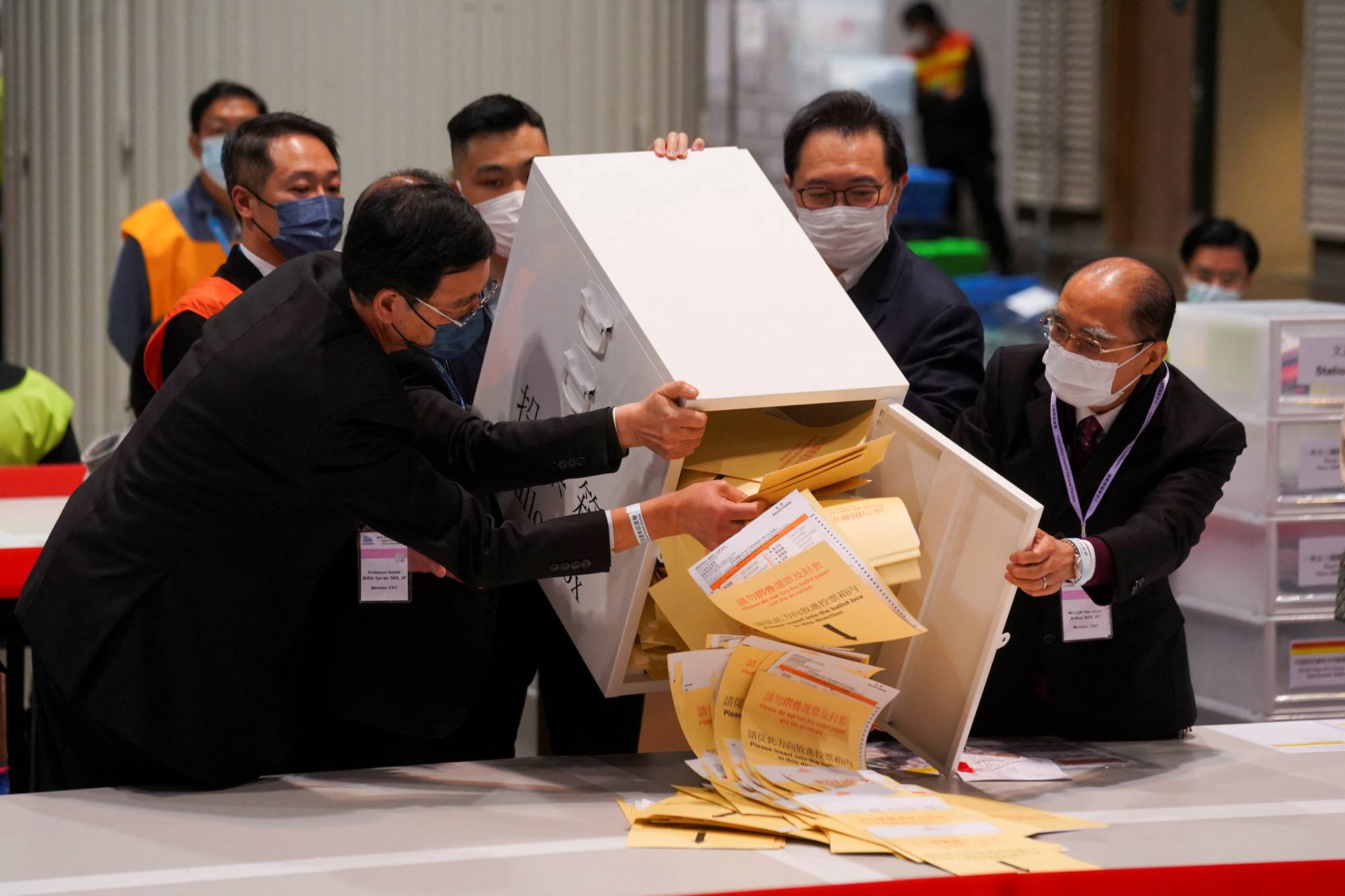 The chairman of Electoral Affairs Commission, Barnabas Fung Wah, and other members of EAC open the ballot box for the Legislative Council election at a vote counting center, in Hong Kong on Dec. 19, 2021. | REUTERS