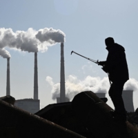 A worker uses a torch to cut steel pipes near a coal-powered power station in Zhangjiakou, one of the host cities for the 2022 Winter Olympic Games. China is the world\'s biggest producer of wind turbines and solar panels, and the Winter Olympics is seen as an opportunity to showcase the country\'s green technologies as they seek global markets. | AFP-JIJI