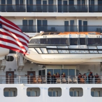 People stand aboard the Queen Mary 2 cruise ship by Cunard Line, owned by Carnival Corporation & PLC. as it is docked at the Brooklyn Cruise Terminal as the omicron coronavirus variant continues to spread in Brooklyn, New York City on Dec. 20, 2021.  | REUTERS