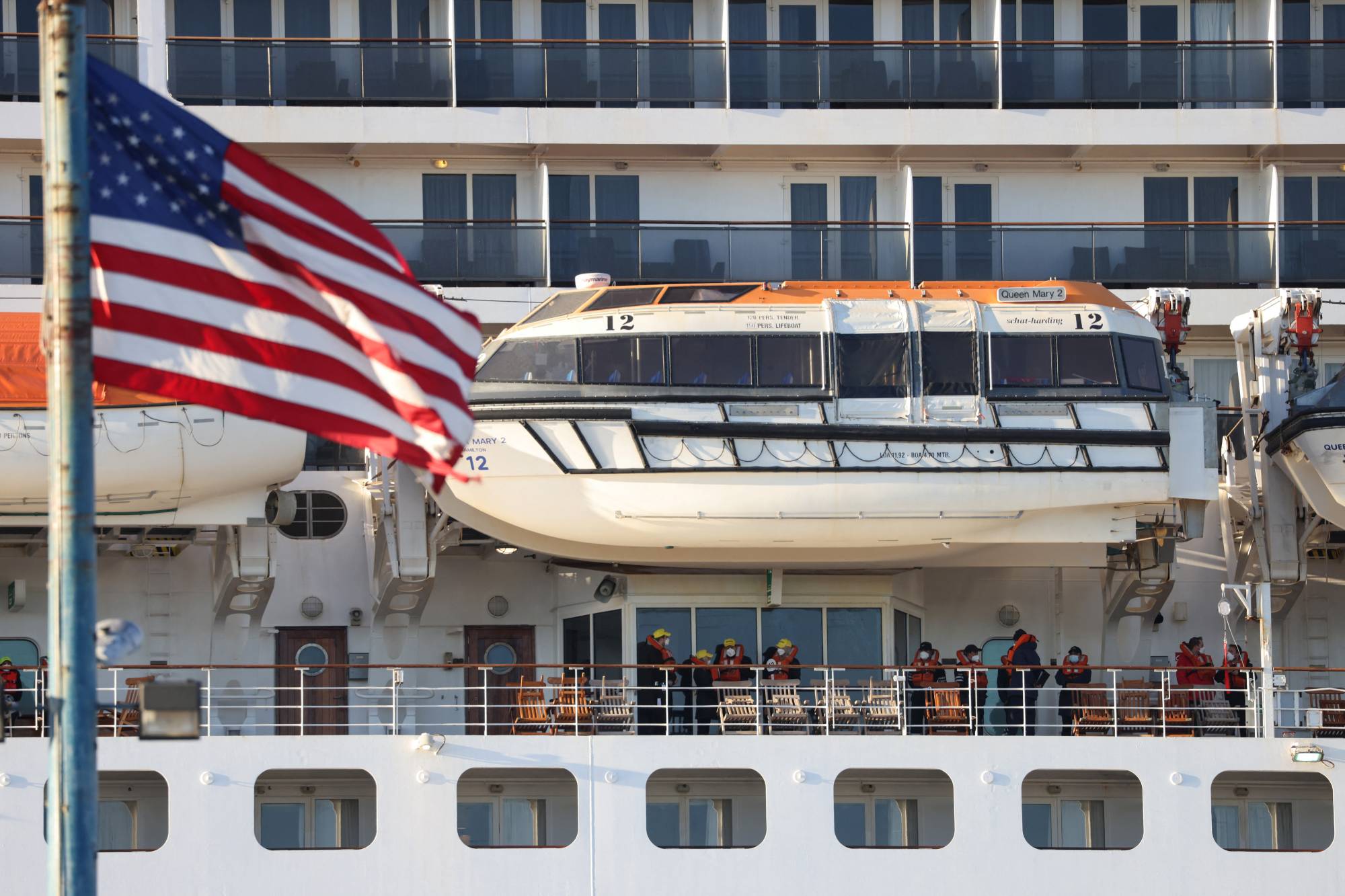 People stand aboard the Queen Mary 2 cruise ship by Cunard Line, owned by Carnival Corporation & PLC. as it is docked at the Brooklyn Cruise Terminal as the omicron coronavirus variant continues to spread in Brooklyn, New York City on Dec. 20, 2021.  | REUTERS
