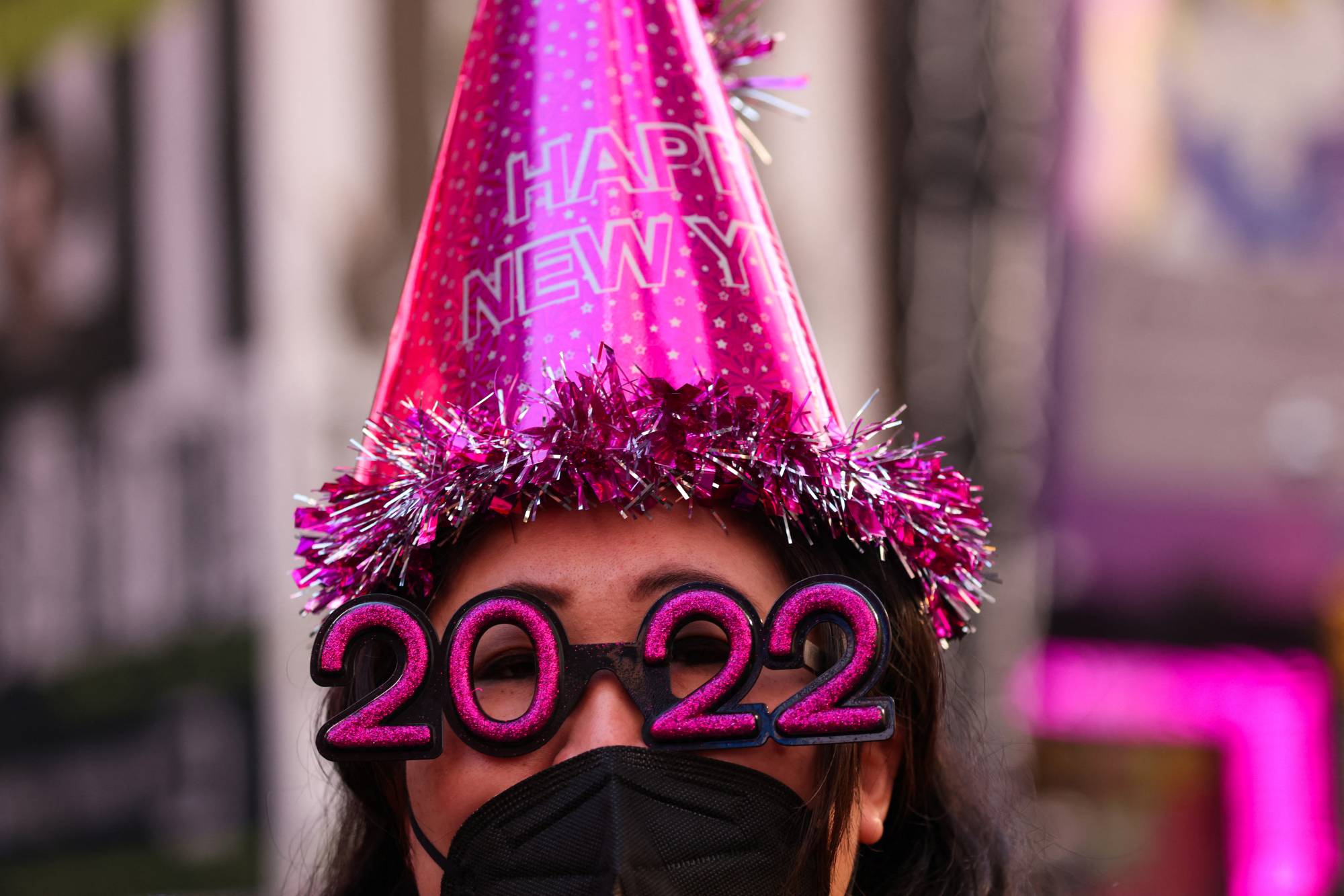 Teresa Hui, 40, of Brooklyn, wears 2022 numeral glasses and a face mask in Times Square ahead of New Year's Eve celebrations as the omicron coronavirus variant continues to spread in Manhattan, New York City on Dec. 20, 2021. |  REUTERS
