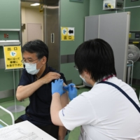 A doctor receives a booster shot of the Pfizer-BioNTech COVID-19 vaccine at Chiba University Hospital in Chiba on Nov. 30. | BLOOMBERG