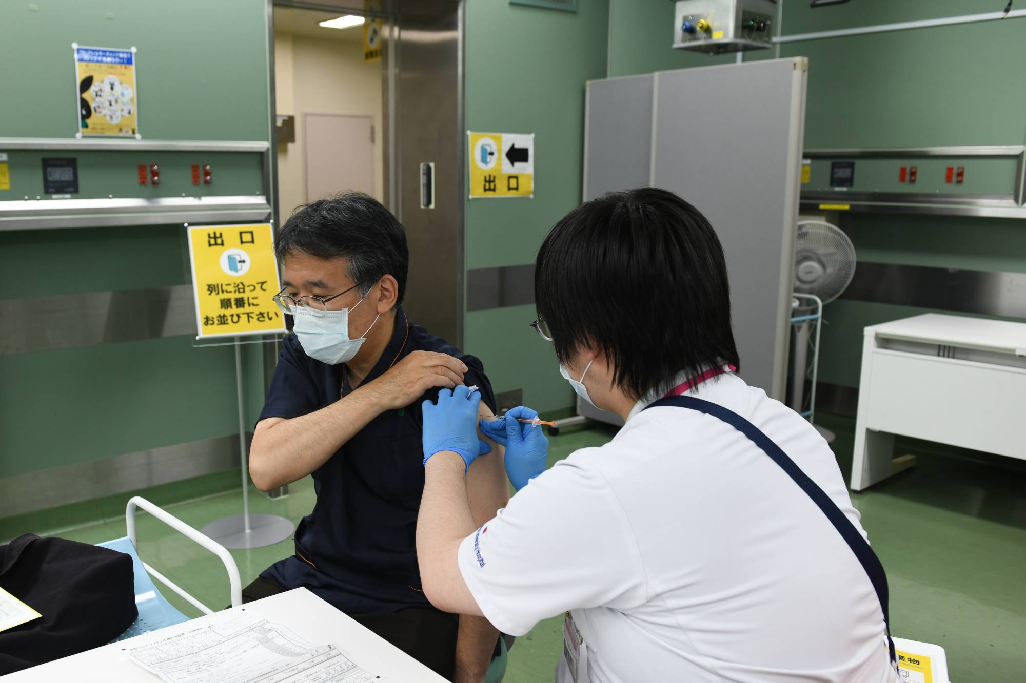 A doctor receives a booster shot of the Pfizer-BioNTech COVID-19 vaccine at Chiba University Hospital in Chiba on Nov. 30. | Bloomberg