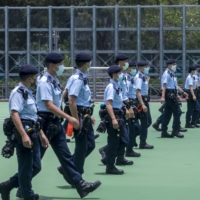 Police officers walk in formation to close off soccer fields at Victoria Park, an assembly point for a banned protest, in Hong Kong in July. | BLOOMBERG 