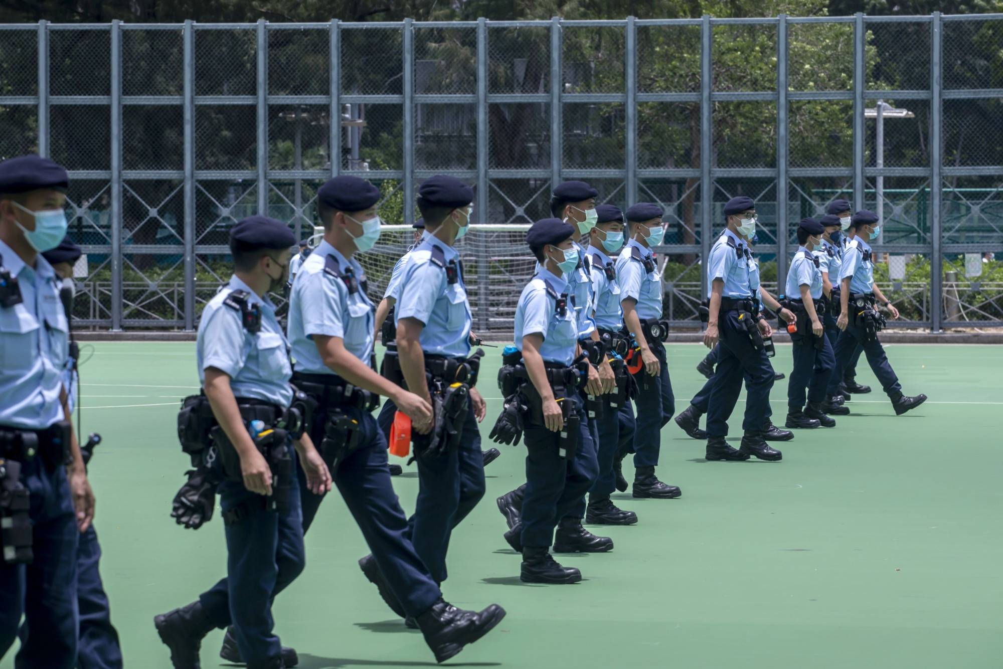 Police officers walk in formation to close off soccer fields at Victoria Park, an assembly point for a banned protest, in Hong Kong in July. | Bloomberg 