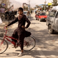 Wafiullah, 15, sits on his bike, which has an Islamic Emirate flag hanging on it, in front of a Taliban checkpoint in Kabul.  | REUTERS