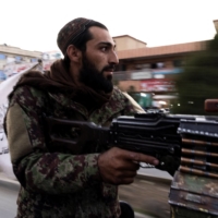 Taliban member Asem, 27, holds a machine gun as he rides on top of a pickup truck during a patrol in Kabul. Asem says he has been a Taliban fighter for the last 12 years. | REUTERS