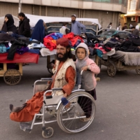 A boy pushes a man\'s wheelchair on a street in Kabul on Oct. 22.  | REUTERS