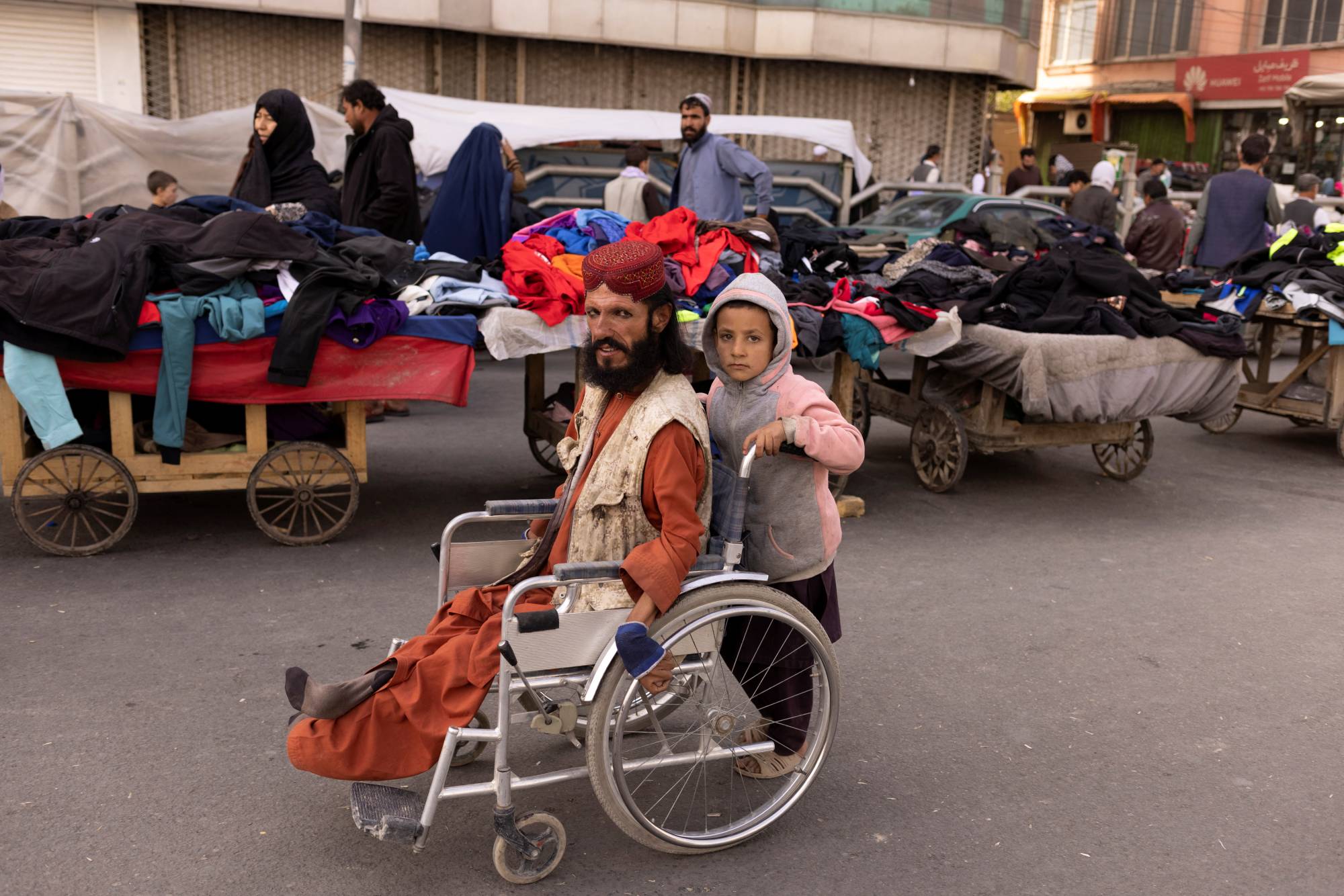 A boy pushes a man's wheelchair on a street in Kabul on Oct. 22. | Reuters