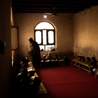 A teacher uses a stick to wake up a boy who fell sleep at a madrasa in Kabul on Oct. 26.  | REUTERS