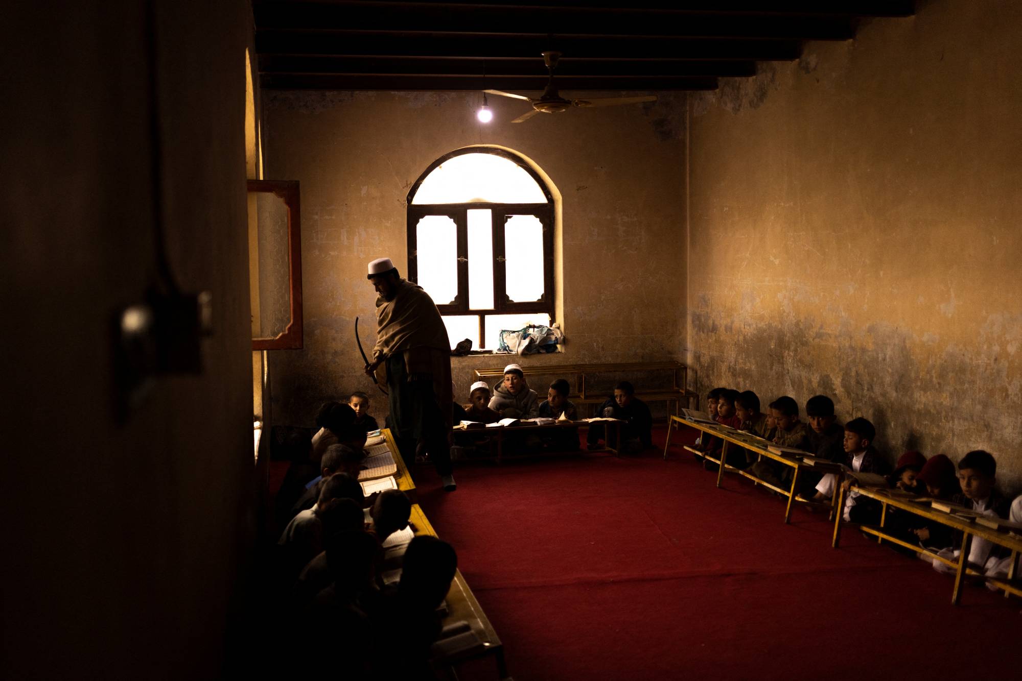 A teacher uses a stick to wake up a boy who fell sleep at a madrasa in Kabul on Oct. 26. | Reuters