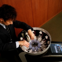 Meiji University professor Homei Miyashita fills flavor canisters as he demonstrates Taste the TV (TTTV), a prototype lickable TV screen that can imitate the flavors of various foods, at the university in Tokyo on Wednesday. | REUTERS
