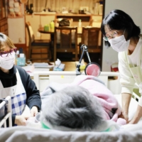 Home-visit care staff tend to an amyotrophic lateral sclerosis (ALS) patient in Sukagawa, Fukushima Prefecture, in Nov. 2020. | KYODO
