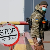 A Ukrainian government border guard mans a checkpoint near the contact line between Ukrainian troops and pro-Moscow rebels in March 2020. | REUTERS