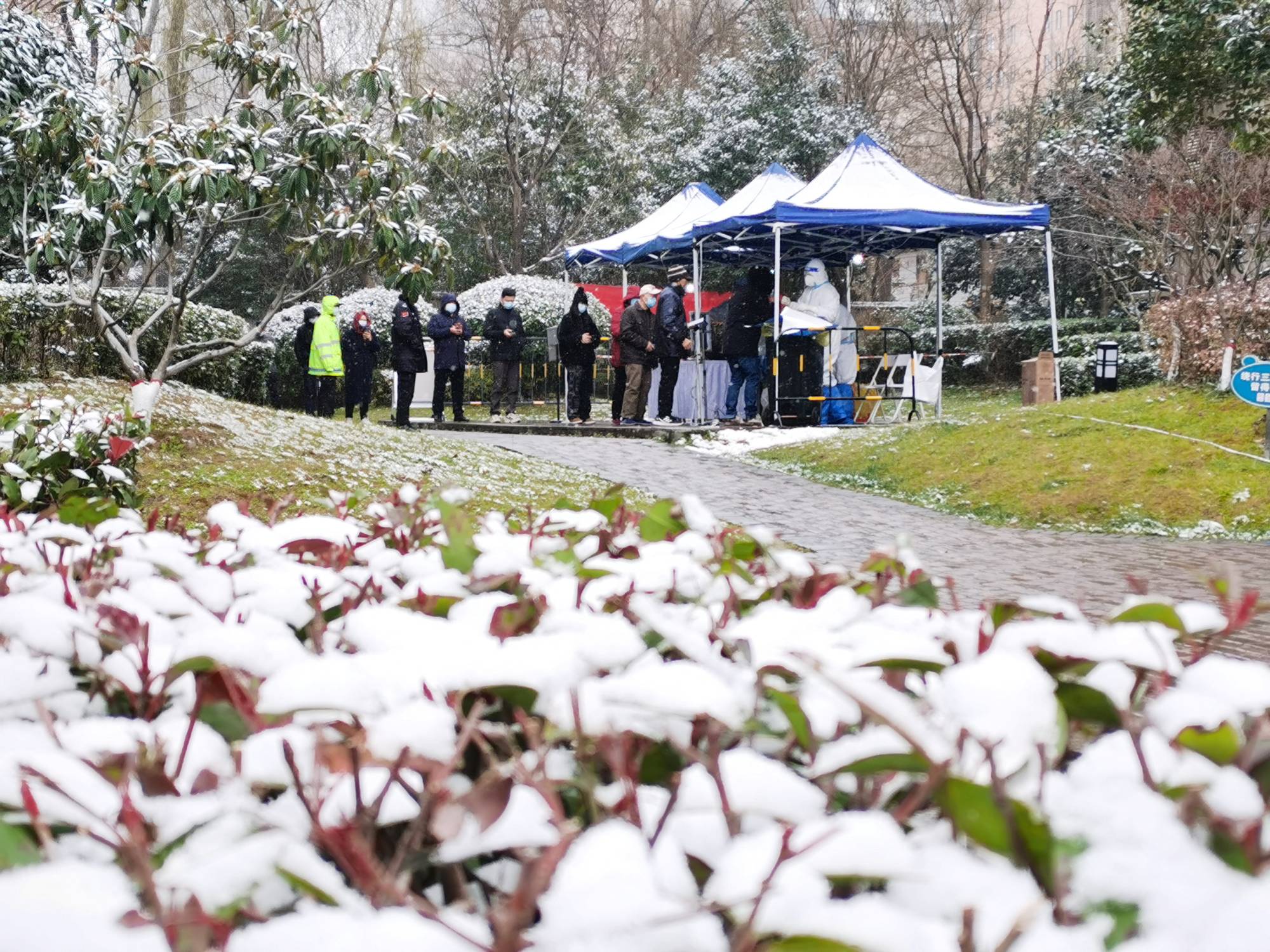 People line up in the snow for nucleic acid testing at a residential compound under lockdown following the COVID-19 outbreak in the Yanta district of Xian, Shaanxi province, China on Dec. 25. | REUTERS 