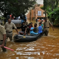 Members of Fire and Rescue Services evacuate people to safer places after heavy rains caused flooding in a residential area in Bengaluru, India, on Nov. 22. | REUTERS