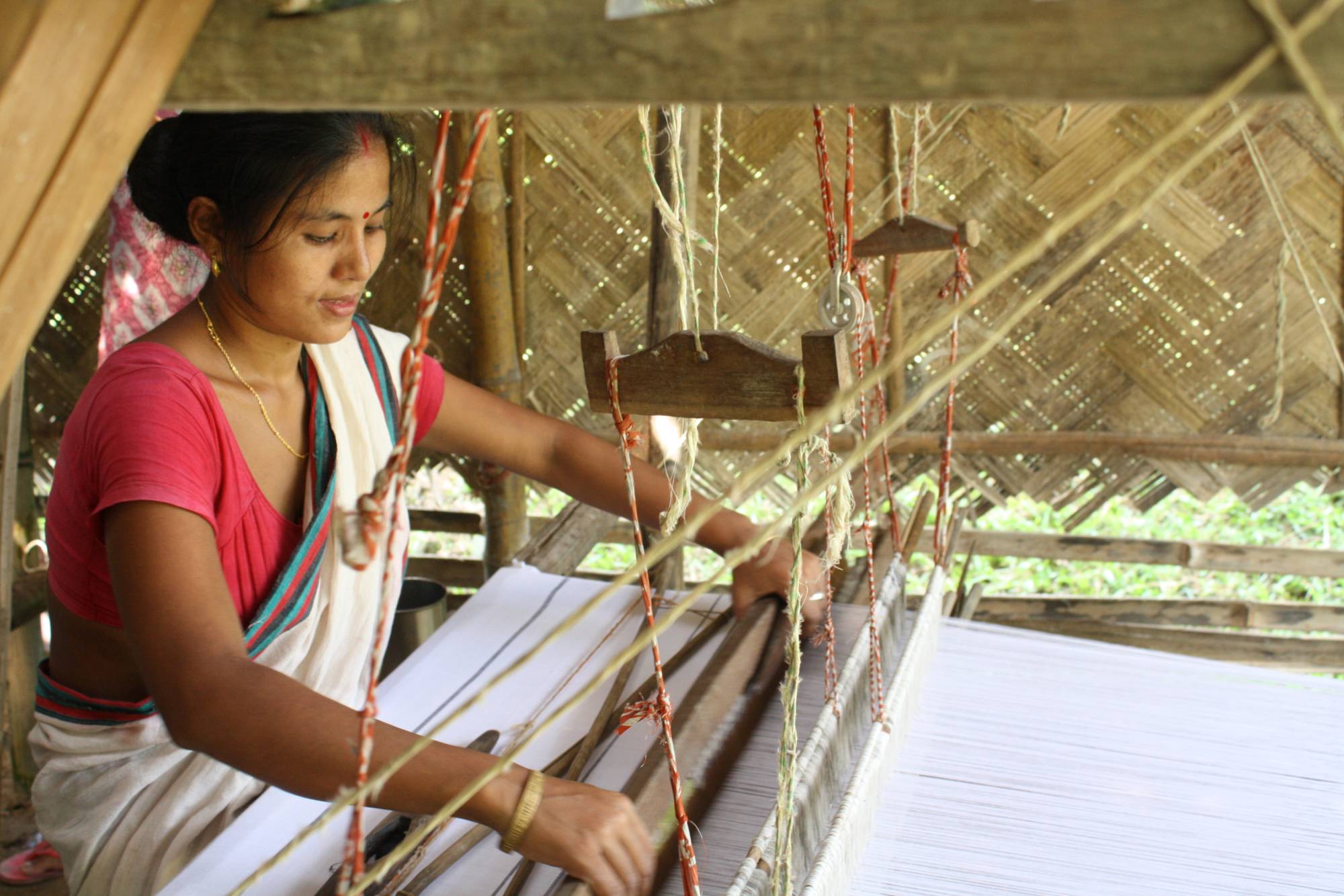 Weaver Rekha Doley works at home in Panbari Mising village in Assam, India. | Impulse Social Enterprises / via Thomson Reuters Foundation