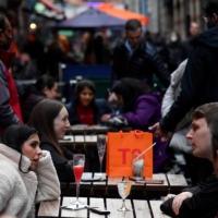 Customers drink in an outdoor seating area of a pub in London on Tuesday. | REUTERS