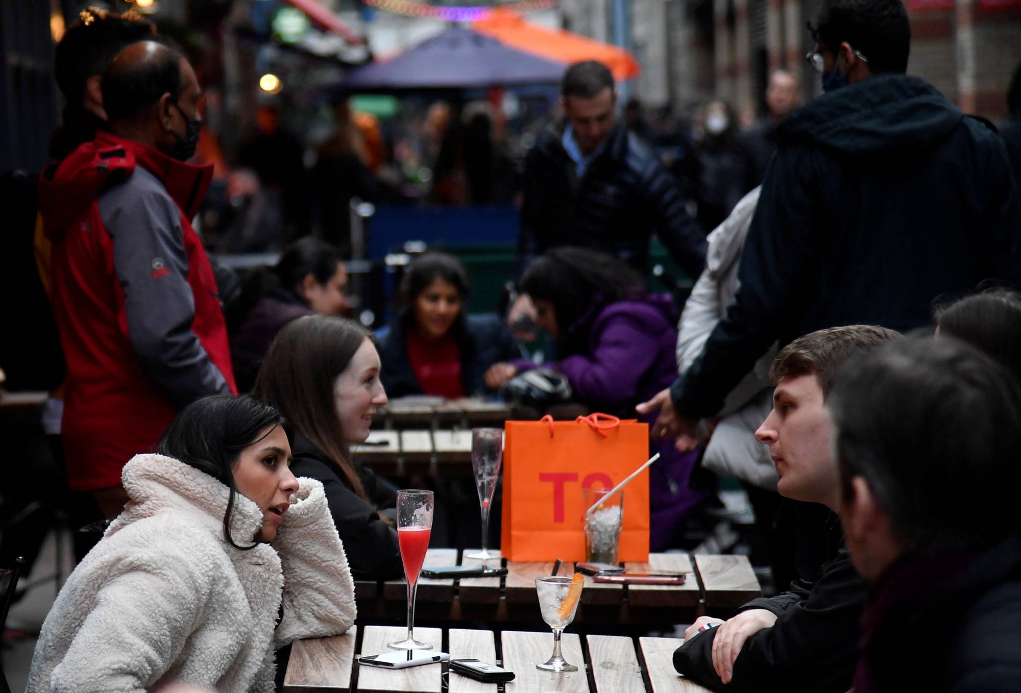 Customers drink in an outdoor seating area of a pub in London on Tuesday. | REUTERS
