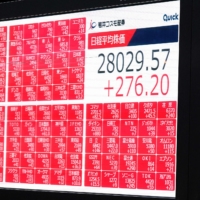 A pedestrian walks past an electronic quotation board displaying the closing share prices of the Tokyo Stock Exchange in Tokyo earlier this month. | AFP-JIJI 