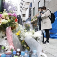 People join hands on Wednesday in front of a building in Kitashinchi, Osaka, where a fatal arson incident took place. | KYODO