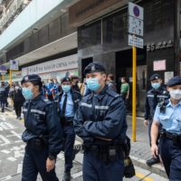 Police officers outside a building that houses the offices of online media outlet Stand News during a raid in Hong Kong on Wednesday. | BLOOMBERG 