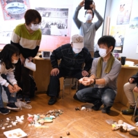Participants of a beachcombing event exchange ideas about objects that were washed ashore. | HOKKAIDO SHIMBUN
