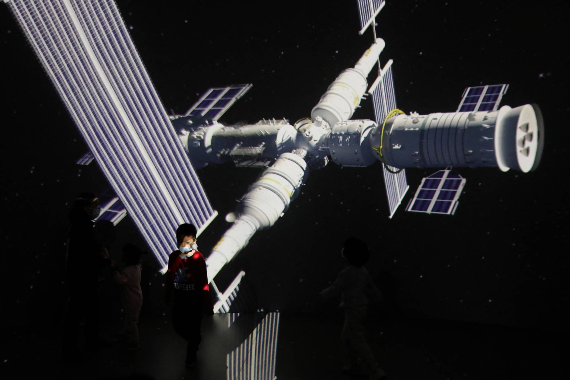 A child stands near a giant screen showing an image of China's Tianhe space station on the country's Space Day in Beijing in April, 2021.  | REUTERS