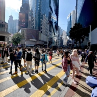 Pedestrians cross a busy intersection in Causeway Bay in Hong Kong on Tuesday. | AFP-JIJI