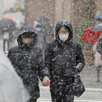 People walk through snow flurries in Tokyo\'s Ginza area on Thursday afternoon. | KYODO