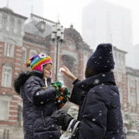 A family plays in the snow outside Tokyo Station on Thursday afternoon. | KYODO