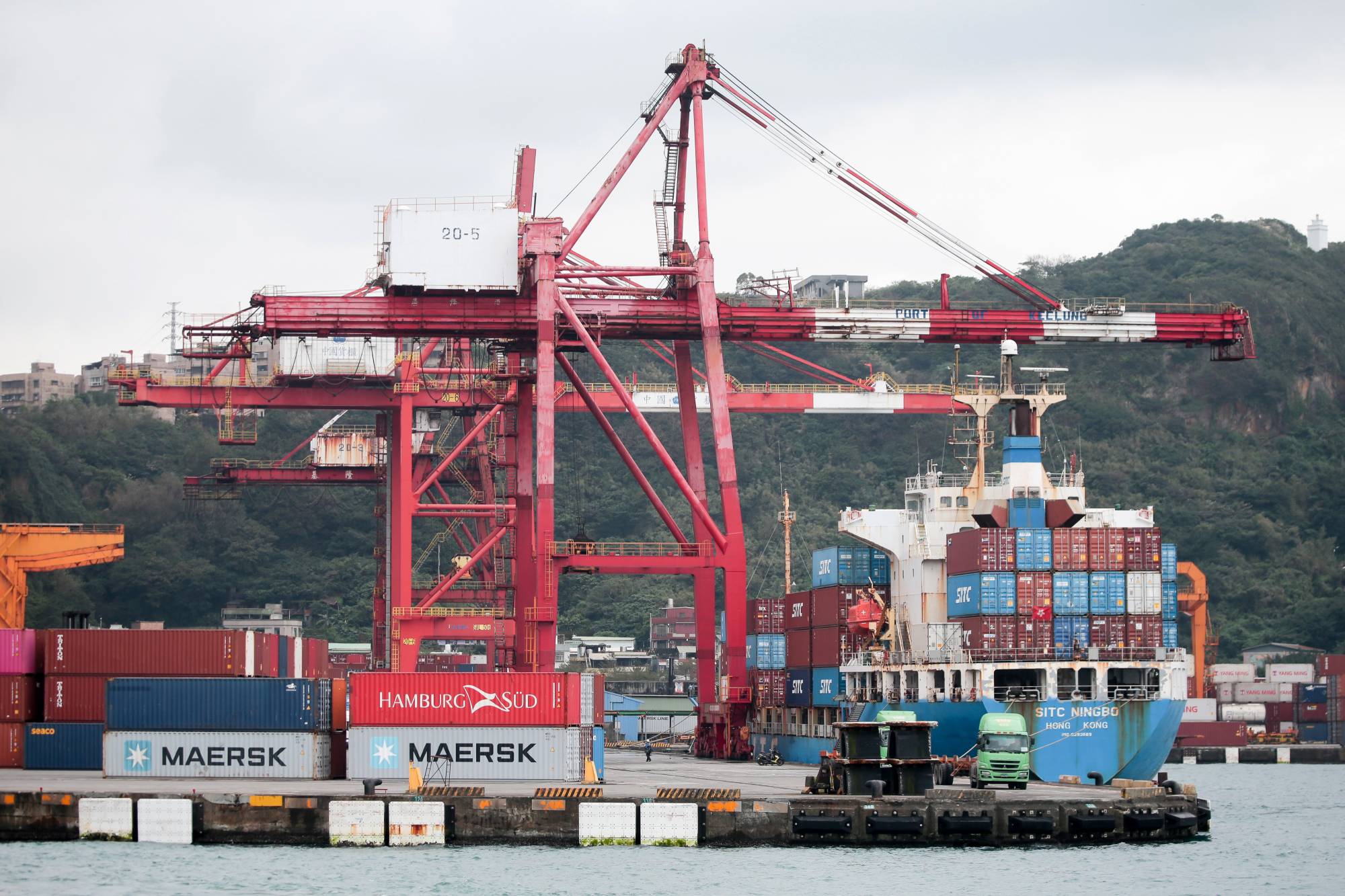 Gantry cranes and a container ship in Keelung, Taiwan, on Jan. 7. Taiwan exports extended their double-digit growth for a tenth month, with shipments from the island in 2021 smashing all records due to soaring demand for technology products and components.  | BLOOMBERG