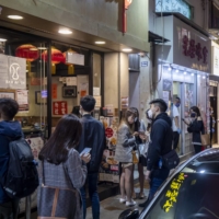 Customers wait for take-out food outside restaurants in the Causeway Bay of Hong Kong on Friday.  | BLOOMBERG 